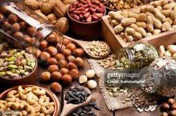 frutos secos (1) Horizontal shot of a rustic wood table filled with a large assortment of nuts like pistachios, hazelnut, pine nut, almonds, pumpkin seeds, sunflower seeds, peanuts, cashew and walnuts. Some nuts are in brown bowls and others in glass jars. Predominant color is brown. DSRL studio photo taken with Canon EOS 5D Mk II and Canon EF 100mm f/2.8L Macro IS USM